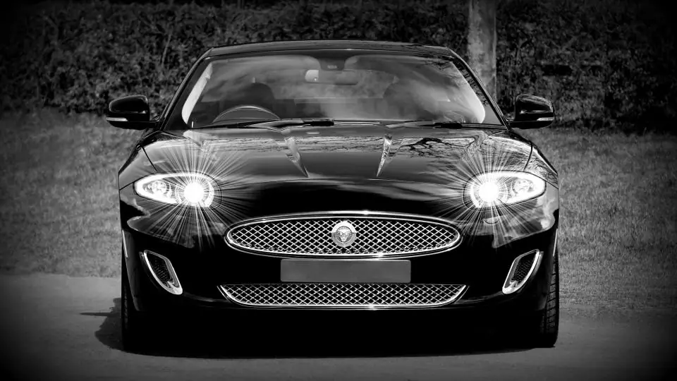 Black coupe seen from the front, headlights on
