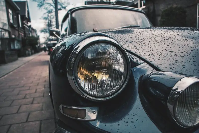 Water beading on the dark paint of a classic car
