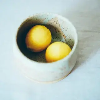 A handmade stoneware bowl holding two lemons