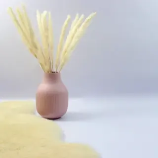 A pink ceramic vase with dried pampas grass